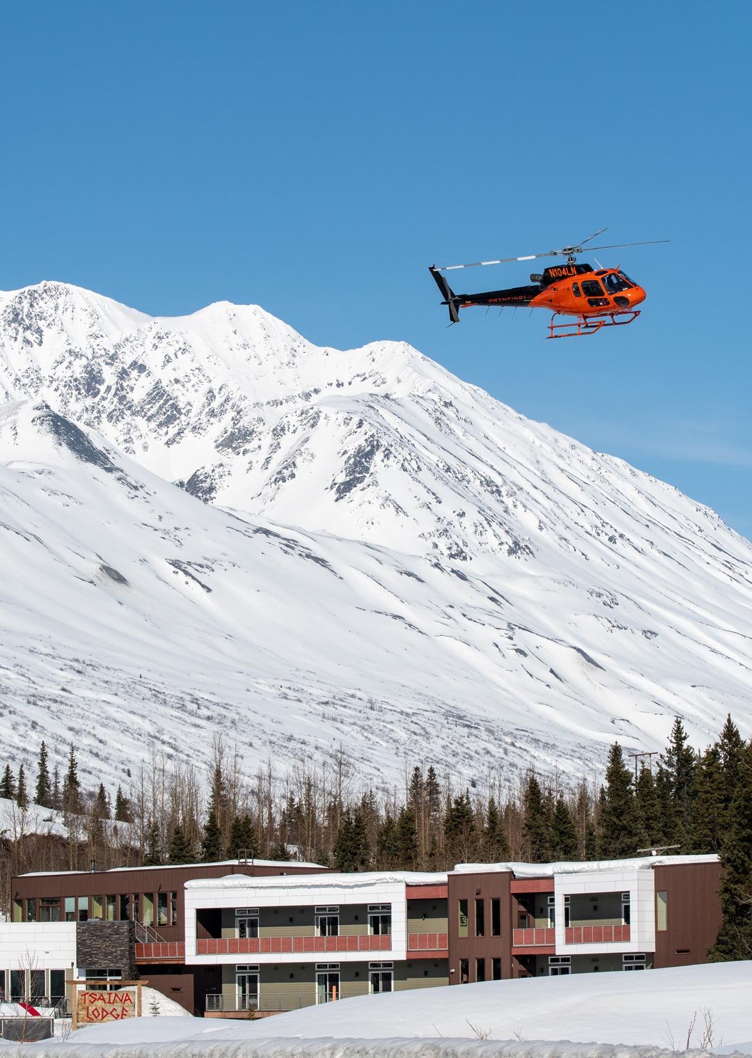 A helicopter flying over the Tsaina Lodge on a clear day