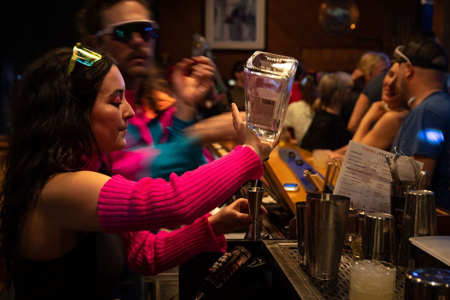 Bartender serving a cocktail to a full crowd at the Tsaina Lodge bar