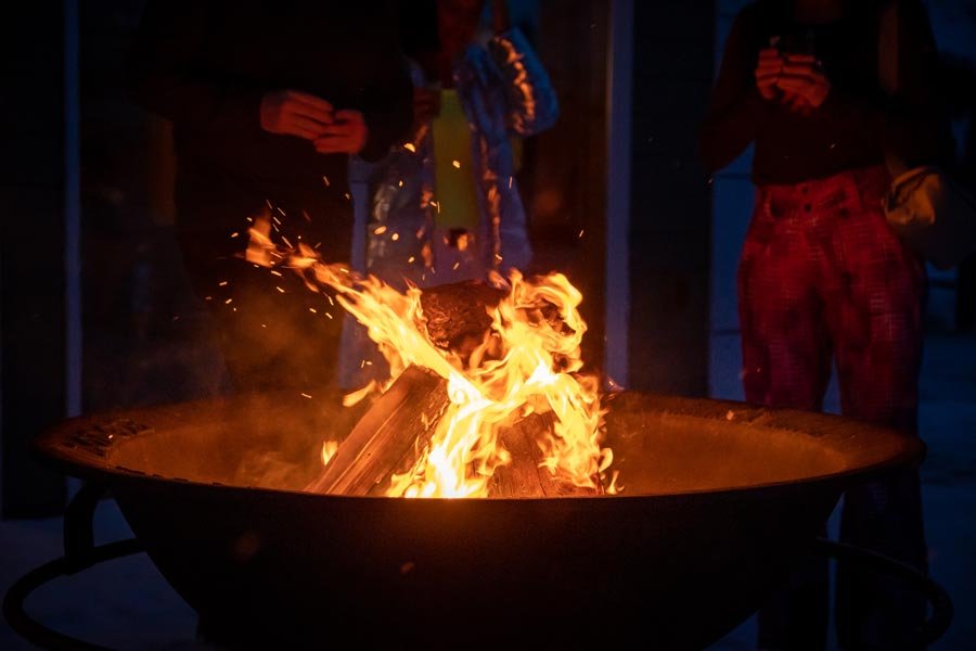 Guests gathered around the lit outdoor fire pit at night
